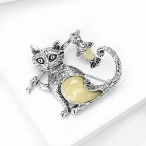 Detail of silver cat brooch with fishing rod design and yellow amber resin stones