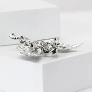 Detailed back view of a silver dragon brooch with star patterns on geometric stand