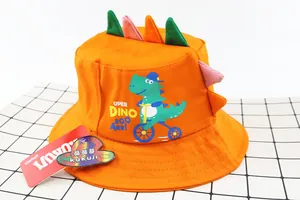 Detail of orange kids sun hat featuring 3D dinosaur spines and cartoon dino print