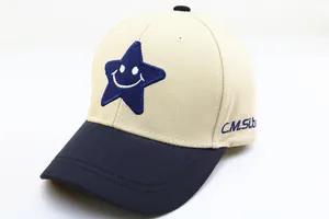 Détail de la broderie étoile bleue et visage souriant sur une casquette enfant en coton