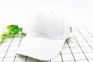 Detail of white cotton baseball cap featuring beige letter A applique and S embroidery