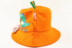 Detail of orange kids bucket hat featuring cartoon dinosaur and 3D decorative horns
