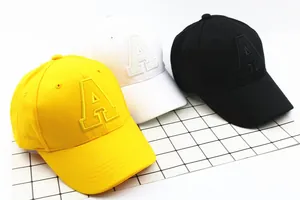 Close-up of children's cotton baseball caps with letter A embroidery in yellow, white, black