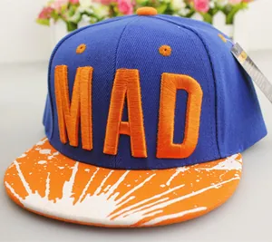 Detalle del bordado MAD y estampado de salpicaduras naranjas en visera de gorra azul