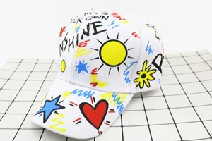 Detailed view of kids white cotton baseball cap featuring colorful graffiti and sunshine text