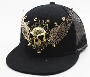 Close-up of a punk style mesh cap featuring a gold skull with wings and metal studs