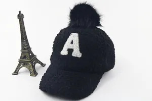 Detail of black faux fur kids baseball cap with white letter A patch and pompom top