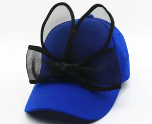 Détail d'une casquette bleue avec oreilles de lapin en résille et un nœud noir élégant