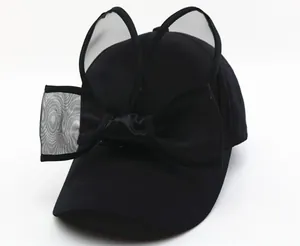 Détail de casquette noire avec oreilles de lapin en mesh et grand nœud satiné