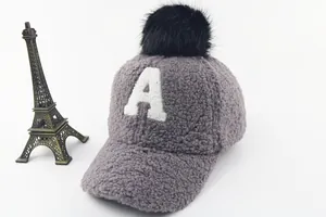 Detail of grey plush kids' winter baseball cap with white A embroidery and black pompom