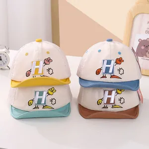 Detalle de gorras tipo trucker de malla para bebé con bordado H y manos de dibujos animados