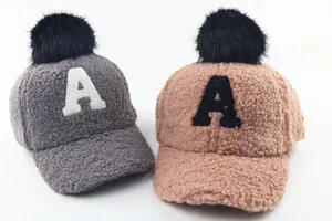 Detail of plush sherpa baseball caps with pom-poms and letter A patch for kids