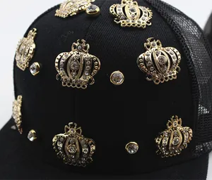 Detail view of golden crown embellishments and rhinestones on black mesh baseball cap