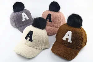 Detail of plush winter baseball caps featuring faux fur pom-poms and letter A embroidery