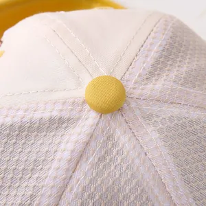 Detalle de la parte superior de la gorra de bebé con botón amarillo y malla transpirable