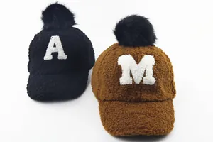 Detail of plush winter baseball caps with furry pom-poms and embroidered letters A and M