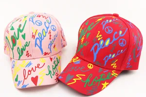 Detail of kids baseball caps featuring colorful graffiti letters and peace sign patterns