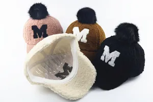 Detailed plush winter baseball hats with fluffy pom-poms and M letter embroidery