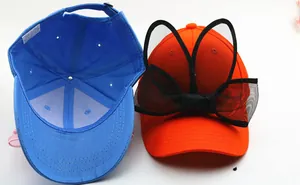 Détail de casquettes en coton avec oreilles en dentelle, étiquette 100% coton et doublure
