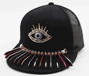 Detail of flat brim baseball cap featuring a golden evil eye and colorful metal charms