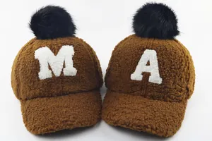 Detailed view of plush teddy fleece caps featuring letter A and M with black fur pom-poms