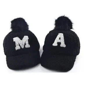 Winter plush baseball cap for kids featuring a large pompom and embroidered letters M and A