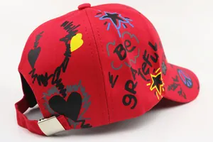 Detail view of red kids baseball cap with graffiti prints and metal adjustable buckle