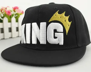 Detail view of the white King embroidery and gold crown on a black flat brim snapback cap