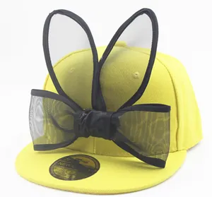 Detail of yellow baseball cap with black mesh bunny ears and a large bow tie
