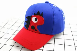 Detail of a kids' blue and red patchwork baseball cap with cartoon dinosaur embroidery