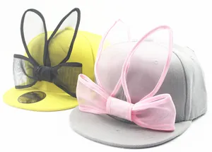 Detail of yellow and grey kids baseball caps with mesh rabbit ears and decorative bows