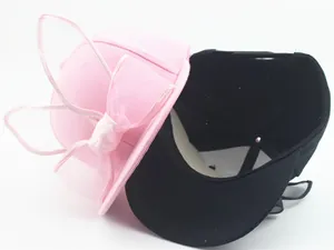 Detail view of cute pink and black baseball caps with large fabric bow decorations