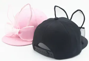 Detail of pink and black baseball caps featuring mesh bunny ears and bowknot decoration