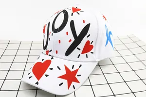 Dettaglio del cappellino bianco con scritte LOVE e JOY e icone graffiti colorate