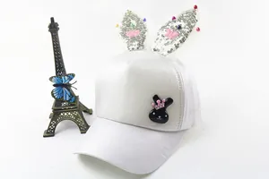 Detail of white girls baseball cap with sequined rabbit ears and a decorative brooch