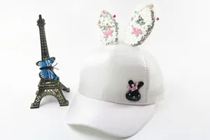 Detail of white kids baseball cap featuring sequin bunny ears and pink bow decoration
