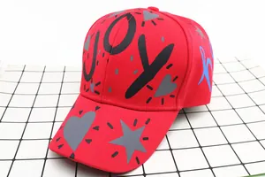 Dettaglio del cappellino rosso in cotone con lettere JOY e motivi a cuore e stella