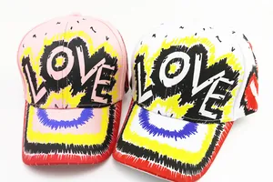 Dettaglio di cappellini da baseball stile graffiti con stampa LOVE e design artistico vivace