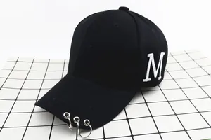 Détail de casquette de baseball noire en coton avec broderie M et anneaux métalliques