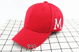 Détail d'une casquette rouge en coton avec broderie M et trois anneaux métalliques