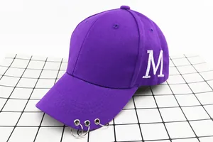 Détail de casquette violette avec anneaux métalliques sur visière et broderie M blanche