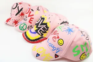 Dettaglio di cappellini da baseball in cotone rosa con motivi graffiti colorati Love e Joy