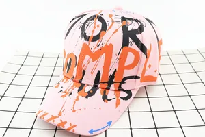 Detailed top view of pink graffiti baseball cap featuring vibrant orange ink splatter art