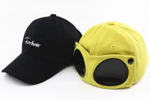 Detail of yellow aviator cap with goggles and black baseball hat with Forever embroidery