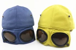 Detail of kids pilot baseball hats with integrated goggles in blue and yellow colors