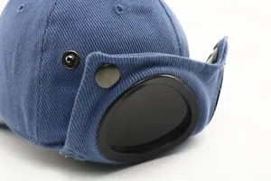 Detail shot of navy cotton twill pilot cap featuring signature black goggle lens on brim