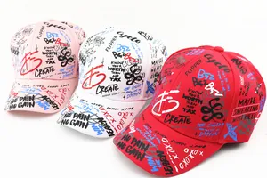 Close-up of children's baseball caps in pink, white, and red with graffiti print