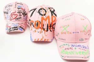 Three pink street-style baseball caps with graffiti prints on a white background