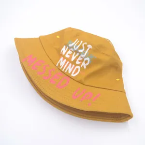 Top view of mustard yellow canvas bucket hat with 'JUST NEVER MIND' printed on crown