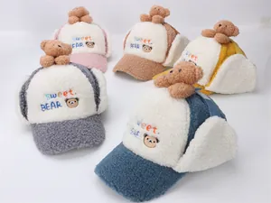 Dettaglio di cappelli con paraorecchie in lana d'agnello con orsetti e ricami dolci